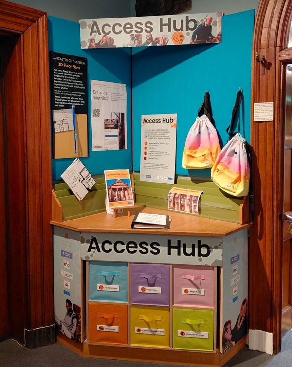 Photo of a colourful corner of a room with backpacks, drawers and other items under a big sign saying Access Hub.